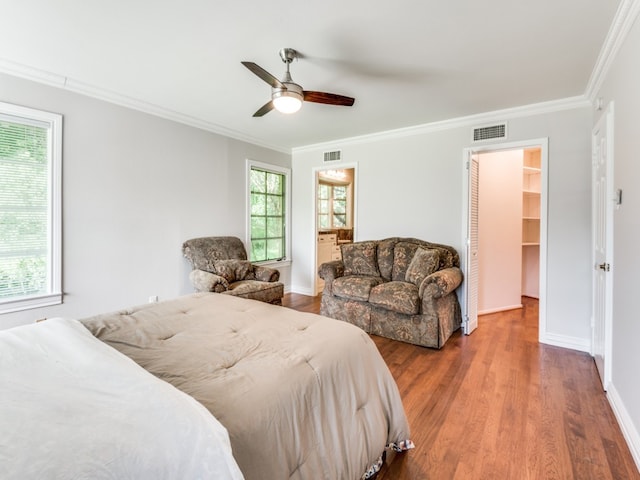 bedroom featuring a spacious closet, crown molding, wood-type flooring, and ceiling fan