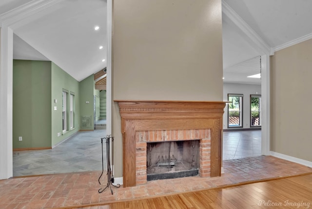 unfurnished living room with ornamental molding, lofted ceiling, hardwood / wood-style floors, and a brick fireplace