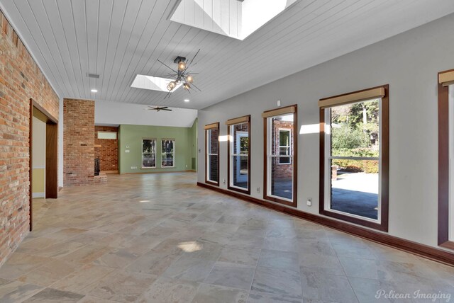 spare room featuring brick wall, wooden ceiling, ceiling fan, and a skylight