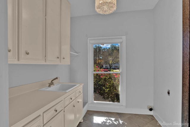 clothes washing area with cabinets, sink, hookup for an electric dryer, and an inviting chandelier