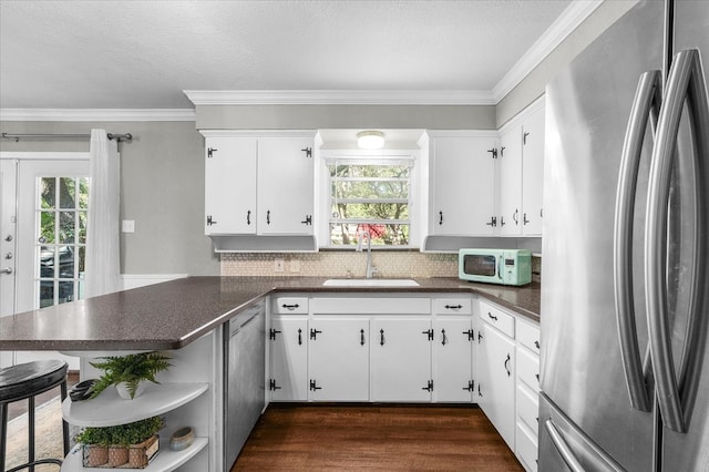 kitchen featuring appliances with stainless steel finishes, kitchen peninsula, white cabinetry, and plenty of natural light