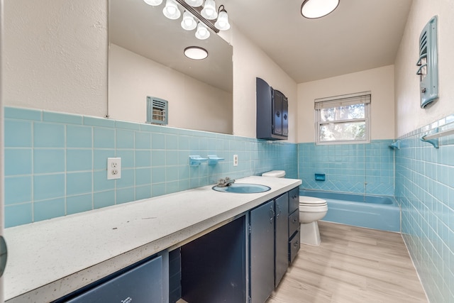 full bathroom with toilet, shower / bathtub combination, vanity, hardwood / wood-style floors, and tile walls