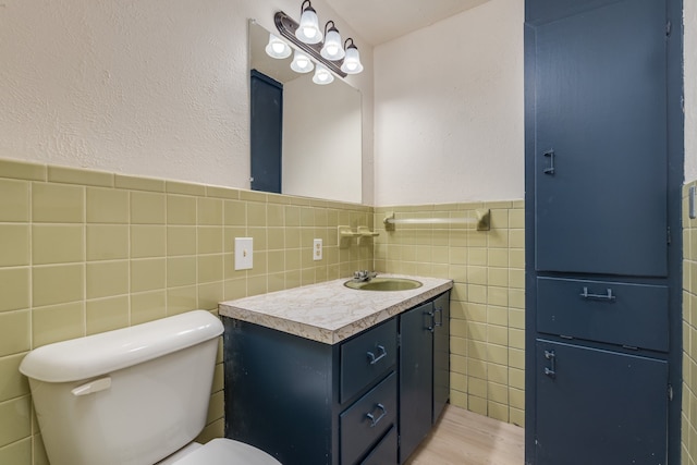 bathroom featuring toilet, vanity, wood-type flooring, and tile walls