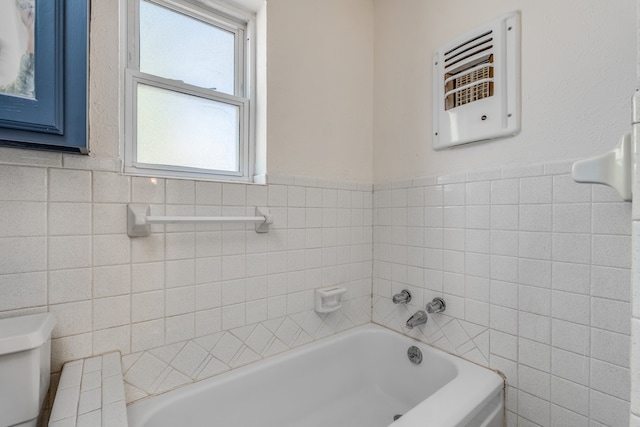 bathroom featuring toilet, tile walls, heating unit, and a bathing tub