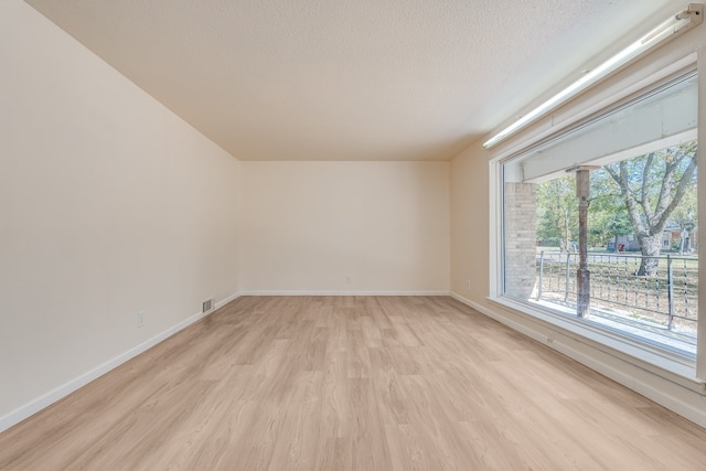 unfurnished room with light hardwood / wood-style floors and a textured ceiling