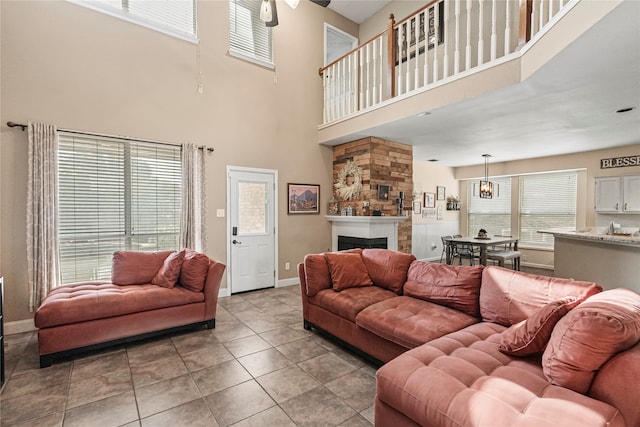 tiled living room featuring a towering ceiling, a fireplace, and ceiling fan