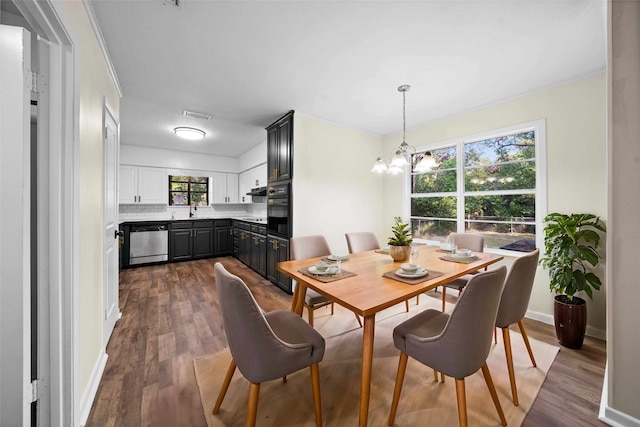 dining room with a notable chandelier, sink, and dark hardwood / wood-style flooring