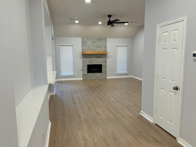 unfurnished living room with ceiling fan, hardwood / wood-style flooring, lofted ceiling, and a fireplace