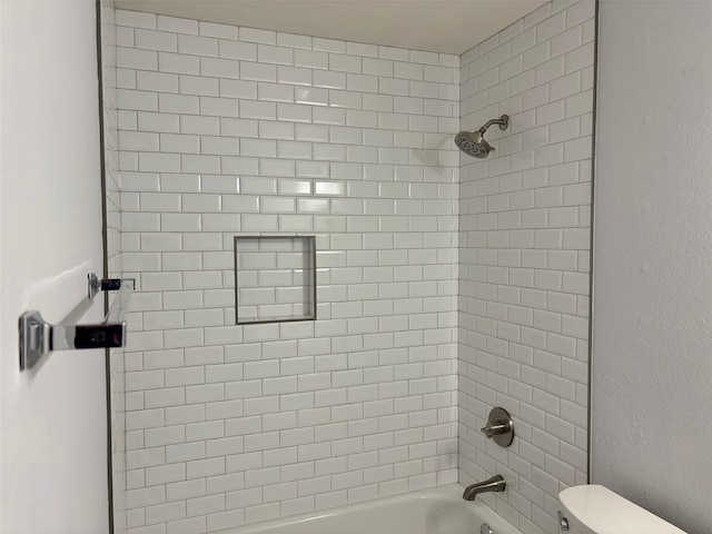 bathroom featuring tiled shower / bath combo and toilet