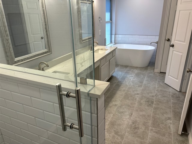 bathroom featuring tile walls, vanity, and a tub to relax in