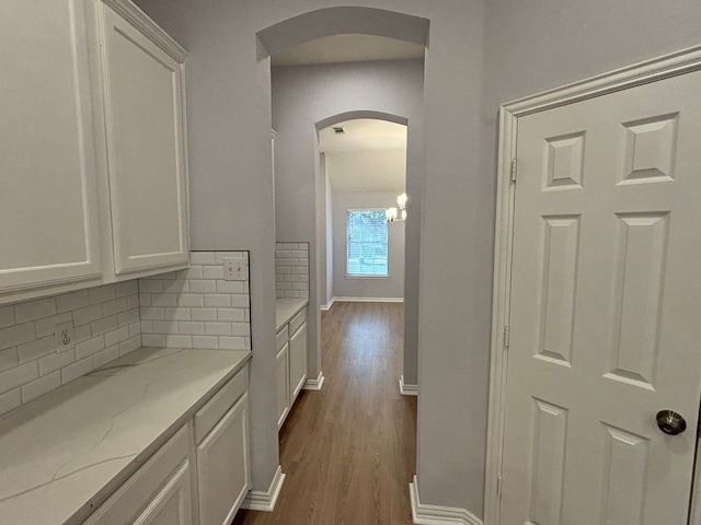 corridor featuring a chandelier and dark wood-type flooring