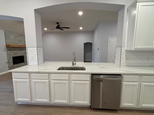 kitchen with sink, dishwasher, light stone countertops, and light hardwood / wood-style floors