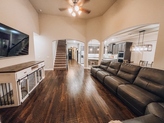 living room with a high ceiling, ceiling fan, and dark hardwood / wood-style flooring