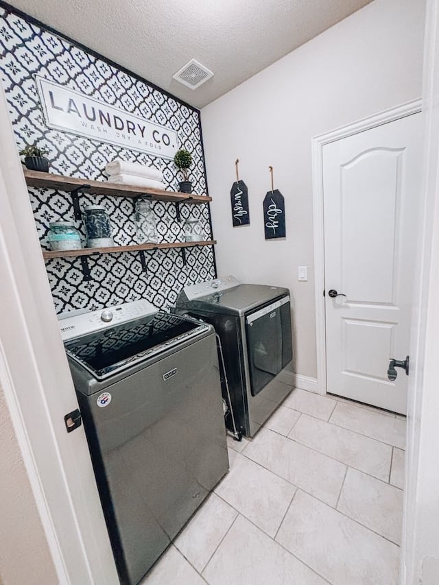 laundry room with light tile patterned flooring, washing machine and dryer, and a textured ceiling