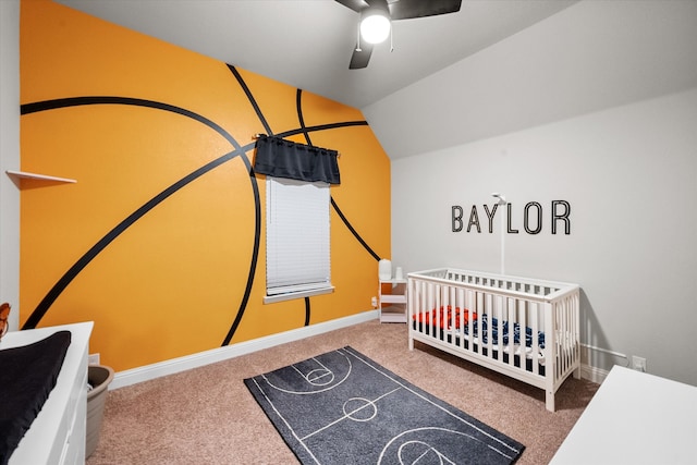 carpeted bedroom with a crib, lofted ceiling, and ceiling fan