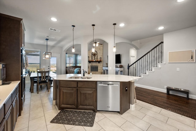 kitchen featuring dishwasher, sink, a kitchen island with sink, and decorative light fixtures