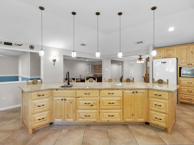 kitchen with decorative light fixtures, sink, an island with sink, and white refrigerator