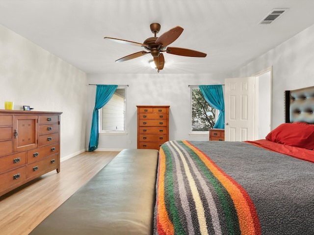 bedroom featuring visible vents, light wood-type flooring, a ceiling fan, and baseboards