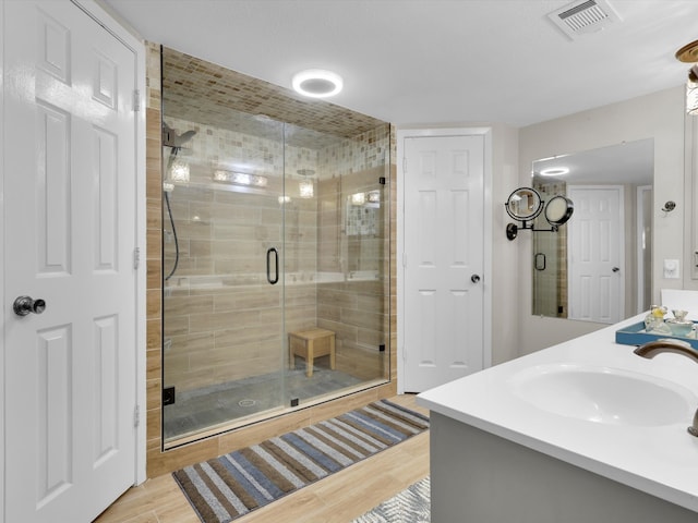 bathroom featuring vanity, wood-type flooring, and a shower with shower door