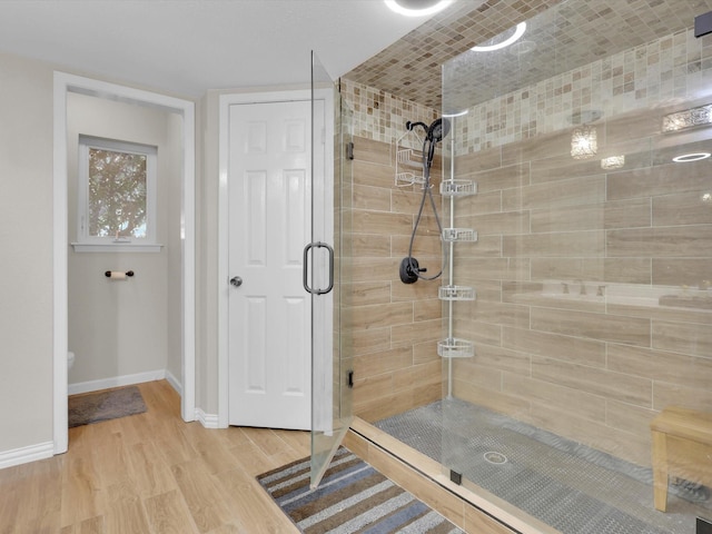bathroom with a stall shower, wood finished floors, and baseboards