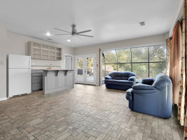 living room featuring french doors, ceiling fan, and sink