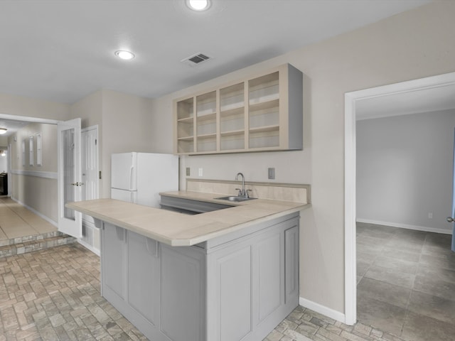 kitchen with white fridge, a kitchen bar, sink, and kitchen peninsula