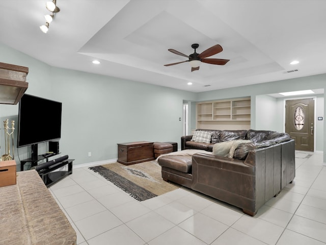 tiled living room featuring a raised ceiling and ceiling fan