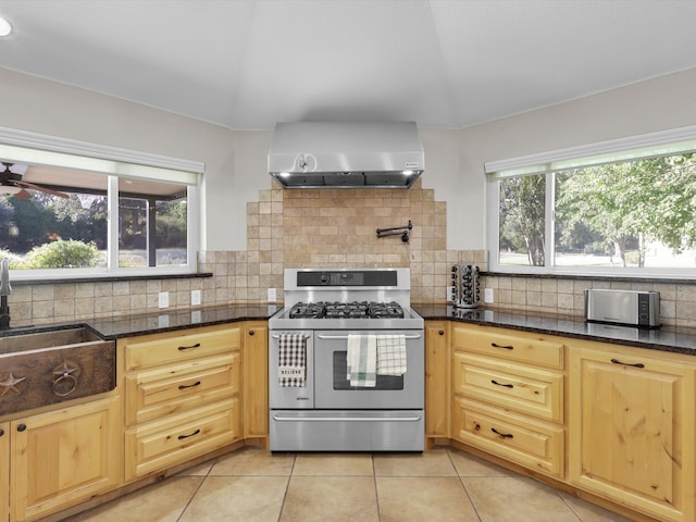 kitchen featuring wall chimney range hood, lofted ceiling, decorative backsplash, and stainless steel range with gas stovetop