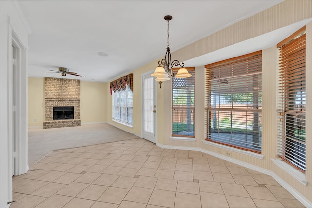 interior space with baseboards, a fireplace, ornamental molding, light carpet, and ceiling fan with notable chandelier