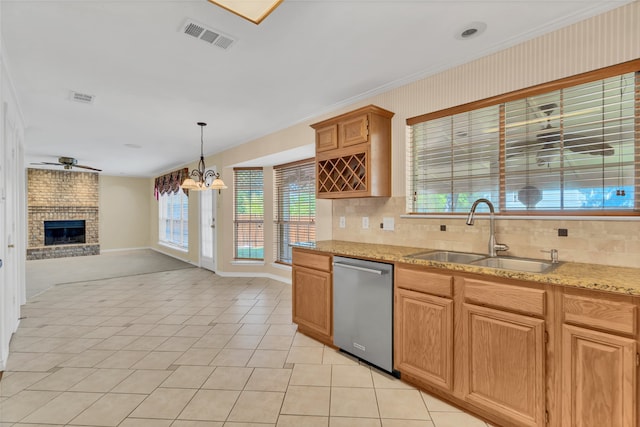 kitchen featuring a fireplace, hanging light fixtures, light tile patterned floors, stainless steel dishwasher, and sink