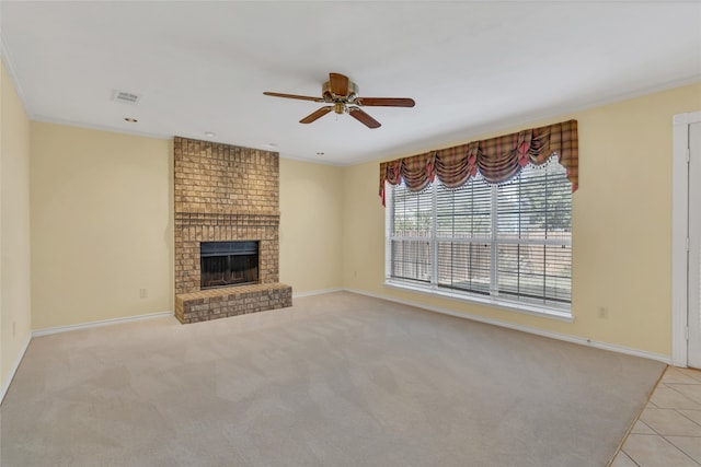 unfurnished living room with a brick fireplace, light carpet, crown molding, and ceiling fan