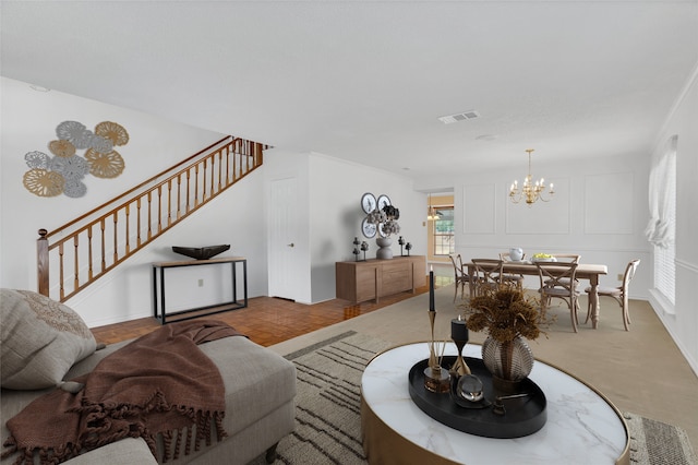 living room featuring stairway, an inviting chandelier, a decorative wall, and visible vents