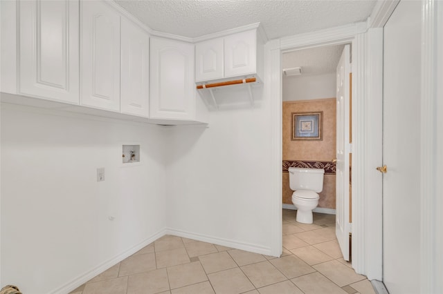 clothes washing area with tile walls, washer hookup, light tile patterned floors, cabinet space, and a textured ceiling