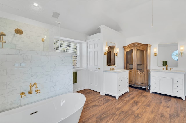 bathroom with visible vents, tiled shower, a soaking tub, and two vanities