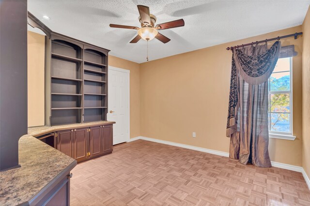 interior space featuring a textured ceiling, light parquet flooring, and ceiling fan