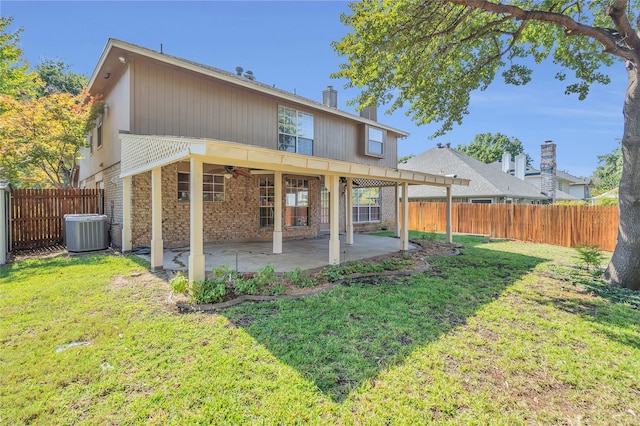 rear view of property with a lawn, a ceiling fan, central AC, a fenced backyard, and a patio area