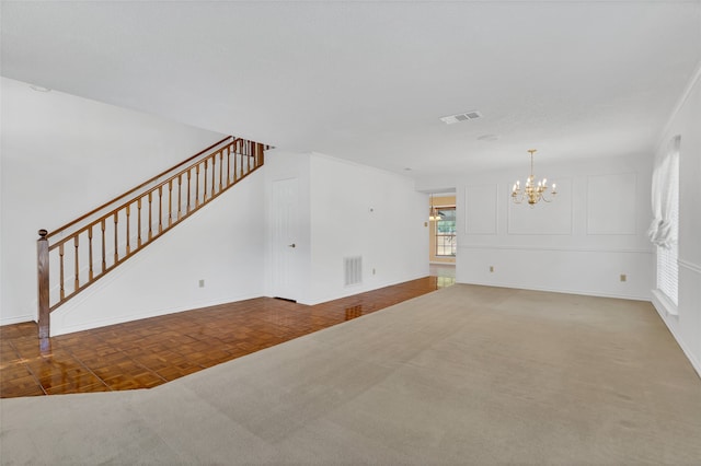 unfurnished living room with a notable chandelier, stairway, baseboards, and visible vents