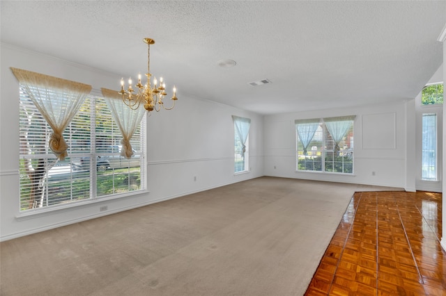 unfurnished living room with visible vents, baseboards, a notable chandelier, and a textured ceiling