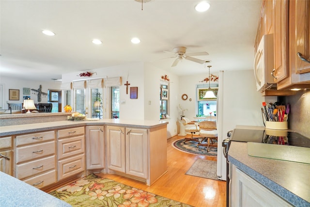 kitchen with light hardwood / wood-style floors, light brown cabinetry, hanging light fixtures, and plenty of natural light