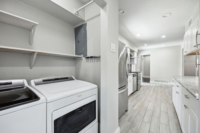 laundry room featuring light hardwood / wood-style floors, electric panel, and washer and clothes dryer