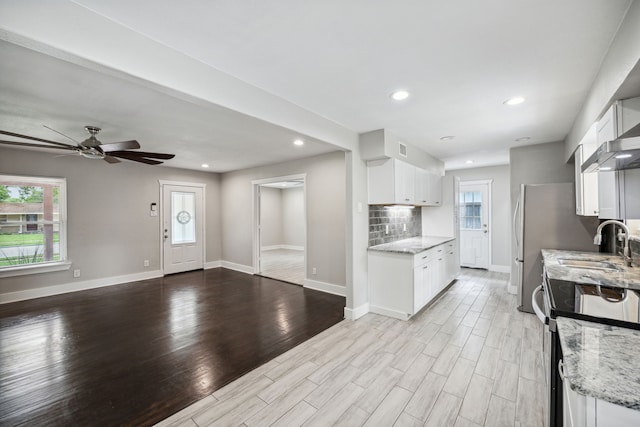 kitchen with light stone countertops, sink, white cabinets, and light hardwood / wood-style flooring