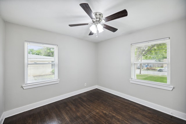 empty room with a healthy amount of sunlight, ceiling fan, and dark hardwood / wood-style flooring