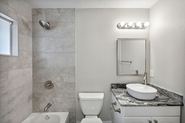 full bathroom featuring vanity, tiled shower / bath, and toilet