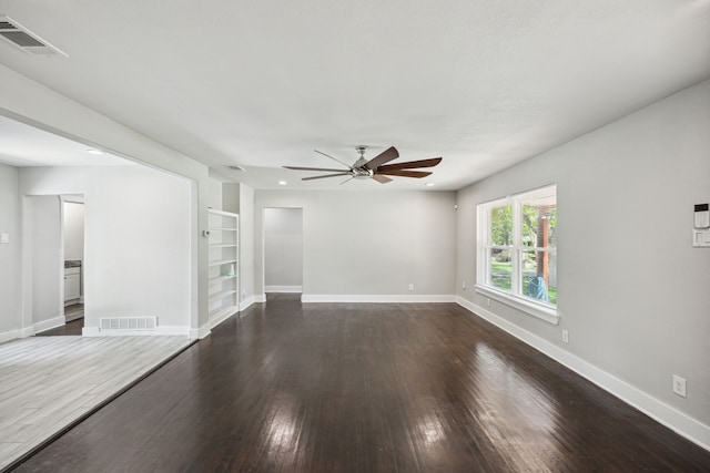 unfurnished living room featuring built in shelves, dark hardwood / wood-style floors, and ceiling fan