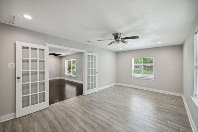 spare room featuring french doors, light hardwood / wood-style flooring, a wealth of natural light, and ceiling fan