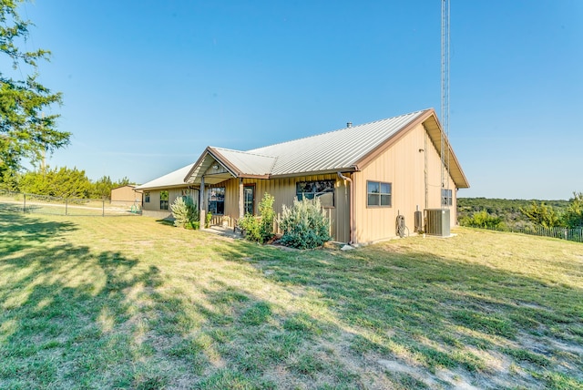 rear view of house featuring cooling unit and a lawn