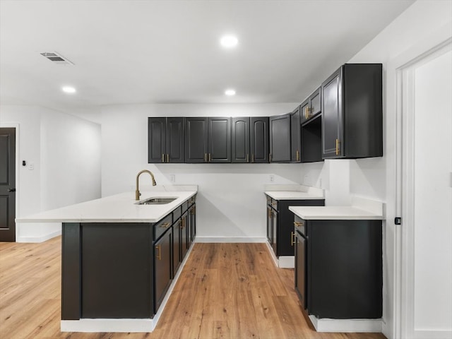 kitchen with kitchen peninsula, light wood-type flooring, and sink