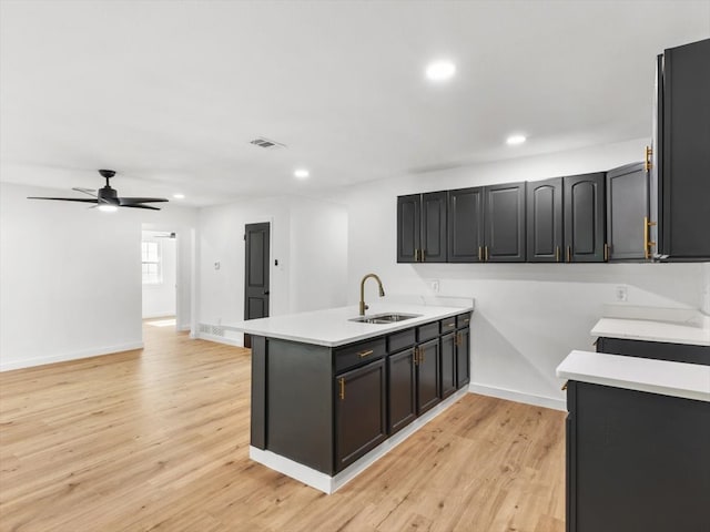 kitchen with sink, ceiling fan, light wood-type flooring, and kitchen peninsula