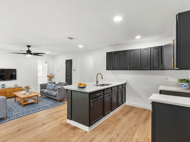 kitchen featuring kitchen peninsula, light wood-type flooring, ceiling fan, and sink