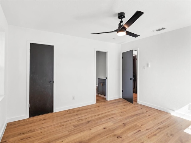 unfurnished bedroom with a closet, ensuite bath, light wood-type flooring, ceiling fan, and a walk in closet